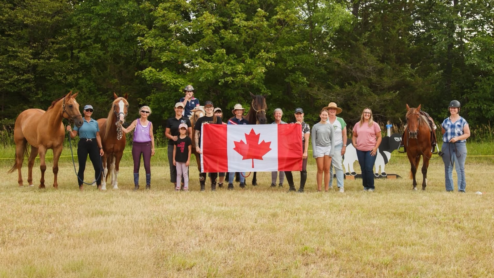 Working equitation club members and their horses posing with a Canadian flag.